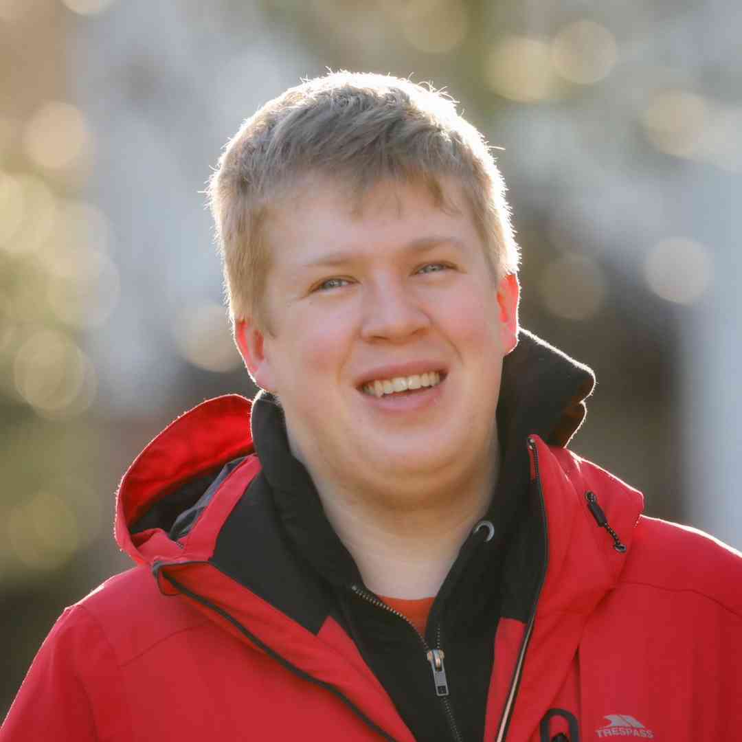 A bokeh photo of Matthew Stratford outside in a red coat.